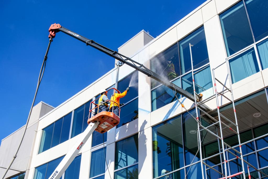 Boom lift crew spray painting a commercial office building exterior in Atlanta, GA
